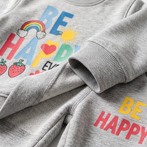 Close-up of a heather gray sweatshirt with a colorful 'BE HAPPY' graphic, including a rainbow, sun, strawberries, and hearts, with the sleeve folded over.