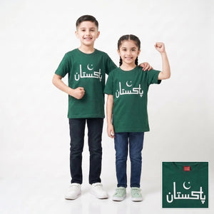 Two children modeling matching dark green t-shirts with white Arabic text and a crescent moon graphic, standing against a light gray studio background. A small inset in the bottom right shows a close-up of the shirt design.