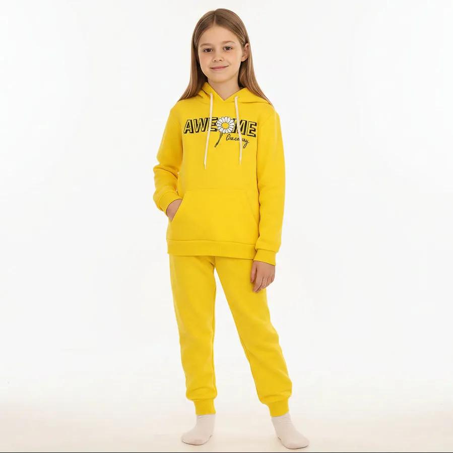 Child wearing a yellow 'Awesome' hoodie and pants in a living room.