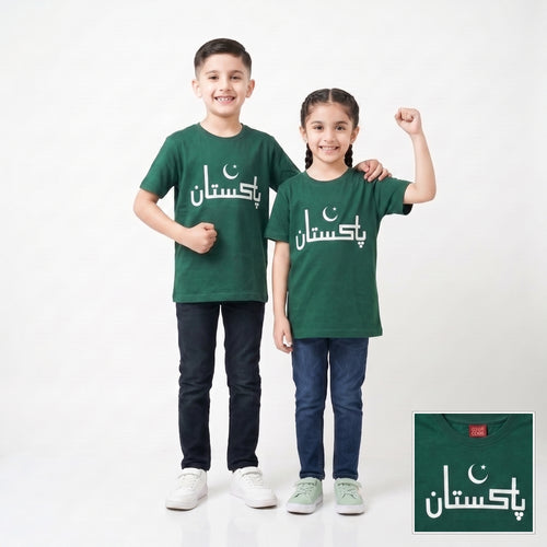 Two children modeling matching dark green t-shirts with white Arabic text and a crescent moon graphic, standing against a light gray studio background. A small inset in the bottom right shows a close-up of the shirt design.