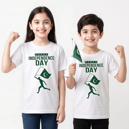 Two children modeling white t-shirts with a green 'HAPPY INDEPENDENCE DAY' graphic and a running figure holding a Pakistan flag. The girl on the left raises her fist, and the boy on the right holds a small Pakistan flag against a plain white background.