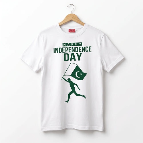 A white short-sleeve t-shirt hanging on a wooden hanger against a plain white background. The shirt features a green graphic print that reads 'HAPPY INDEPENDENCE DAY' above a silhouette of a runner carrying a Pakistan flag.