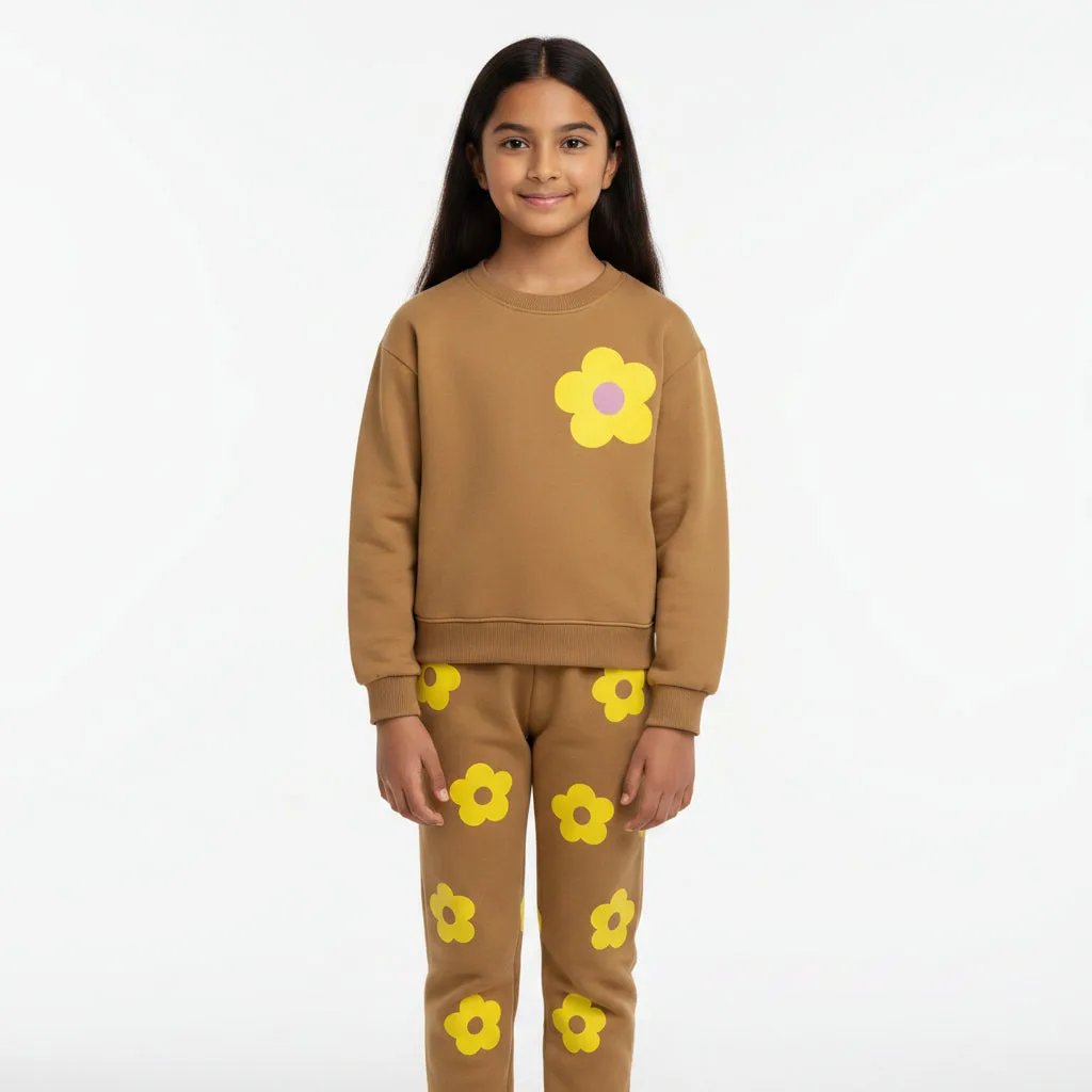 Young girl wearing a brown outfit with yellow flower patterns in a living room.