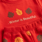 Close-up of a red fleece garment with embroidered autumn leaves and the phrase '. Winter is Beautiful.' in white text.